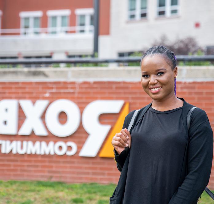 student outside RCC sign in front of campus